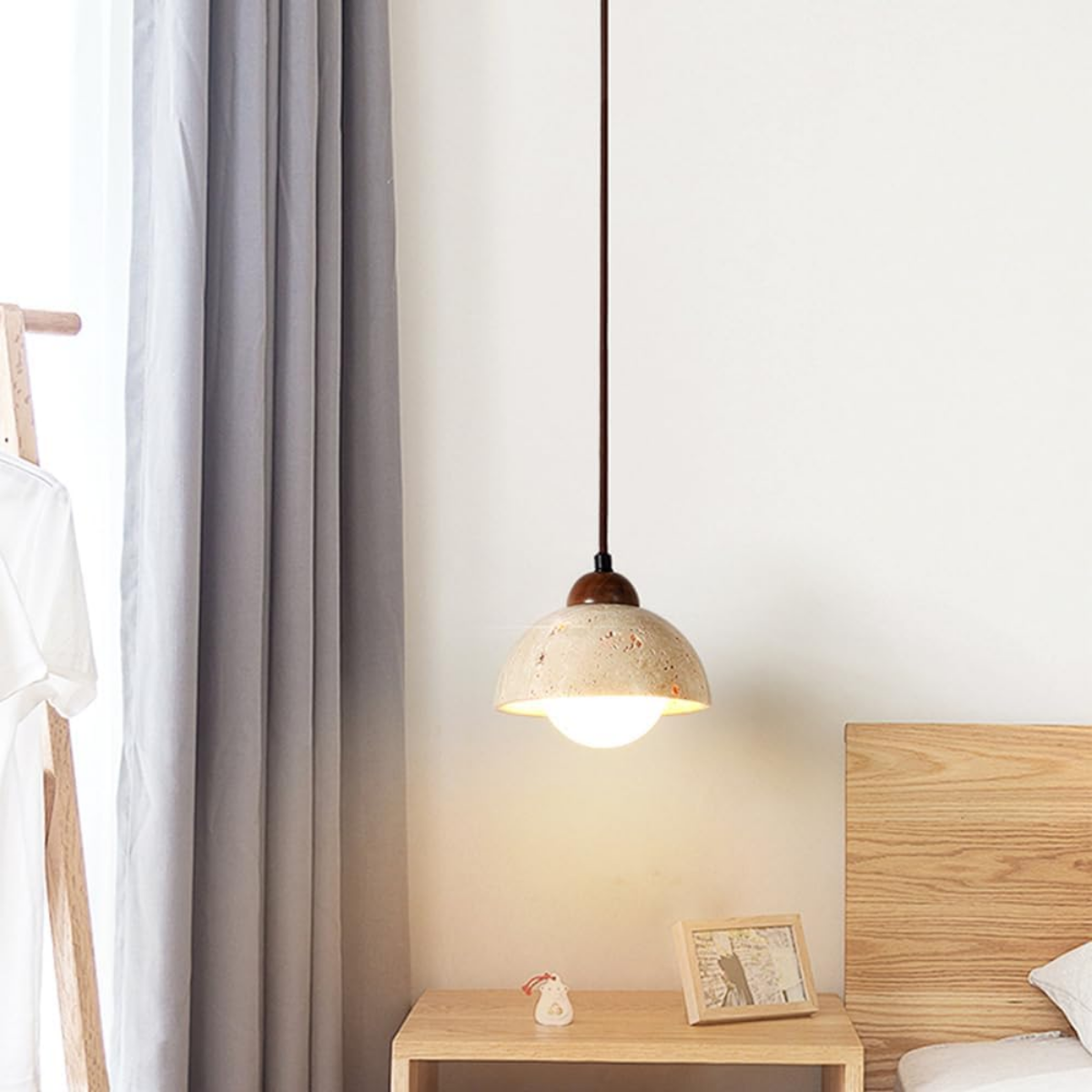 Aurelia Travertine Dome Pendant Light hanging in a bedroom beside a curtain and armchair
