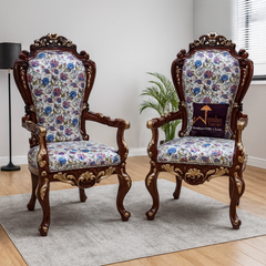 Pair of ornate chairs with floral patterns on a wooden floor.