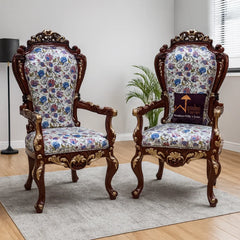 Pair of ornate chairs with floral patterns on a wooden floor.