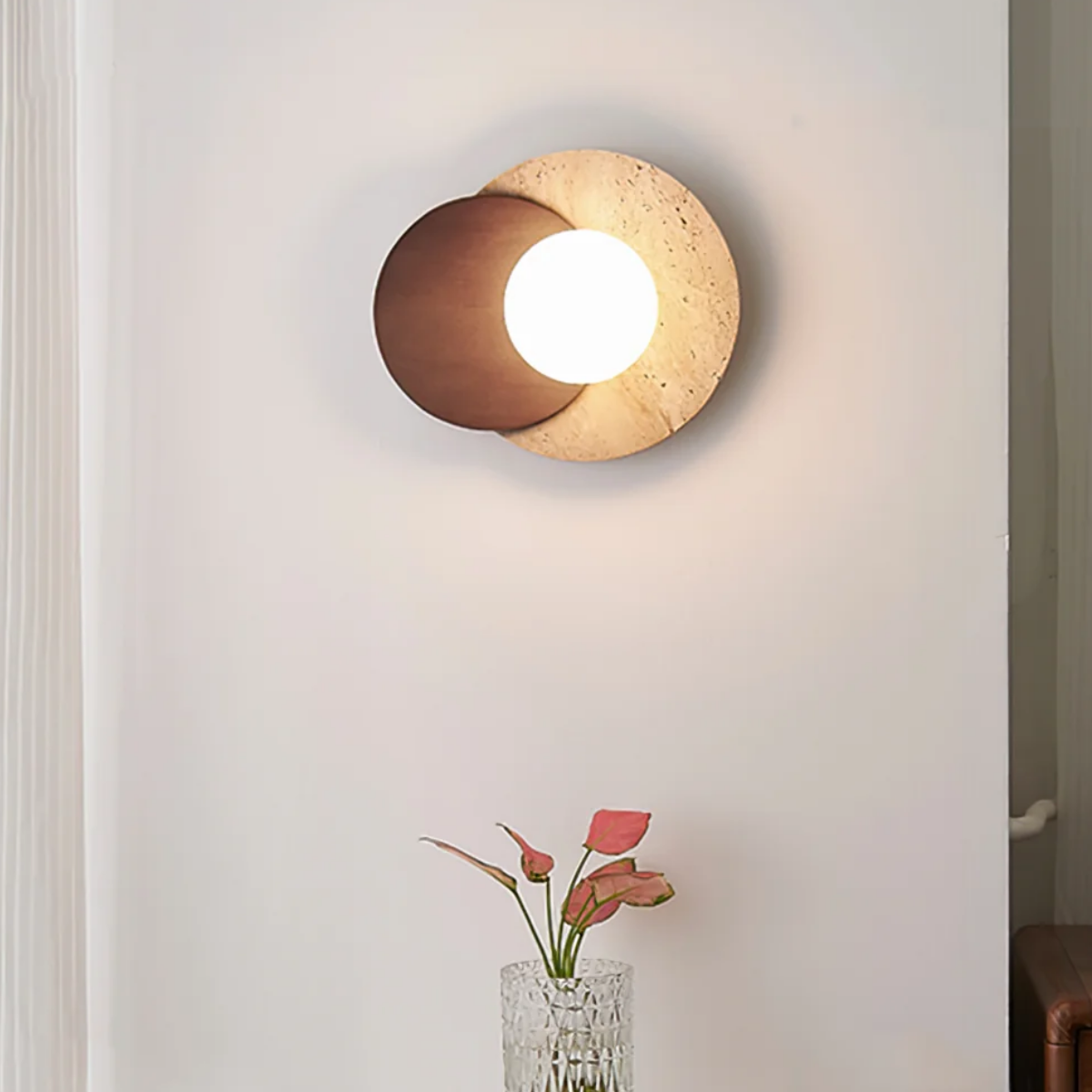 Lunara Travertine Stone & Wood Lunar Eclipse Wall Light installed in a hallway above a console table with flowers