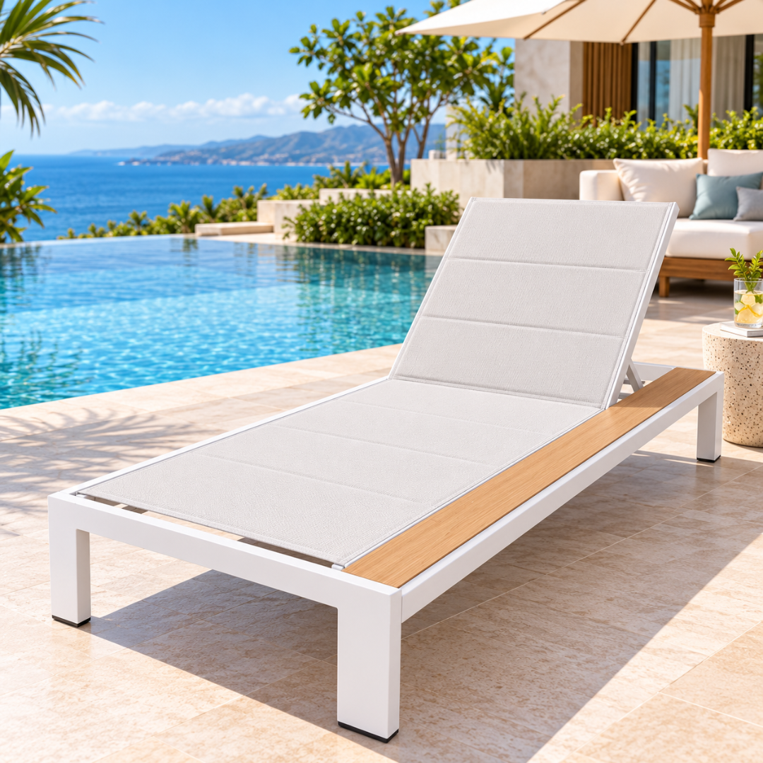 Riviera aluminium sun lounger with quilted sling seat and wood-look side shelf by a sea-view pool