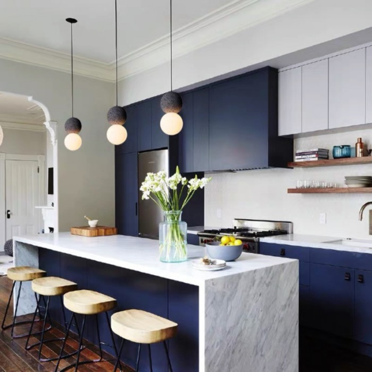 lifestyle three pendants above a navy kitchen island