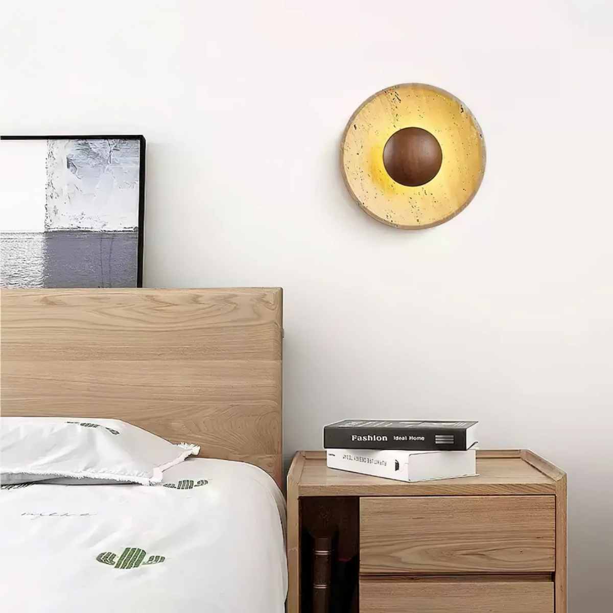 Solara Travertine Round Wall Light installed above a bedside table in a modern bedroom setting