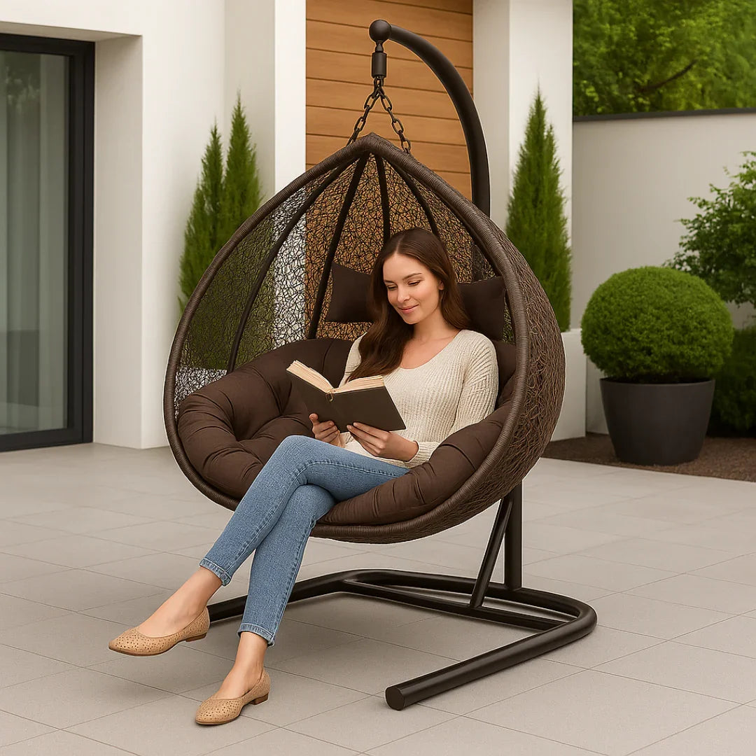 Woman reading a book in a hanging egg chair outdoors.