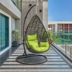 Hanging egg chair with green cushions on a patio area.