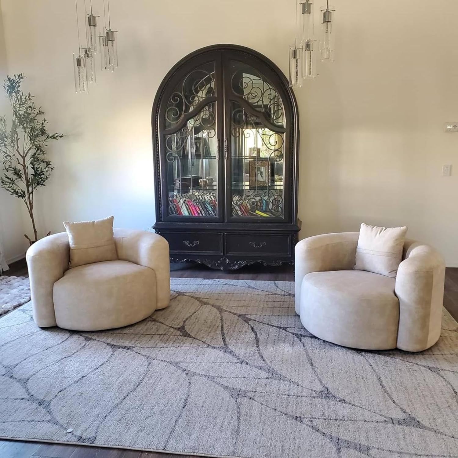 Two beige armchairs in a living room with a decorative mirror and plant.
