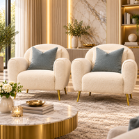 Wooden Twist Aurelle set of 2 cream boucle lounge chairs with gold metal legs and blue-grey cushions in a luxury living room