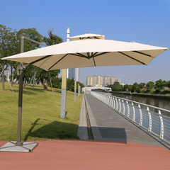 Beige patio umbrella on a stand with a scenic background of a river and trees.