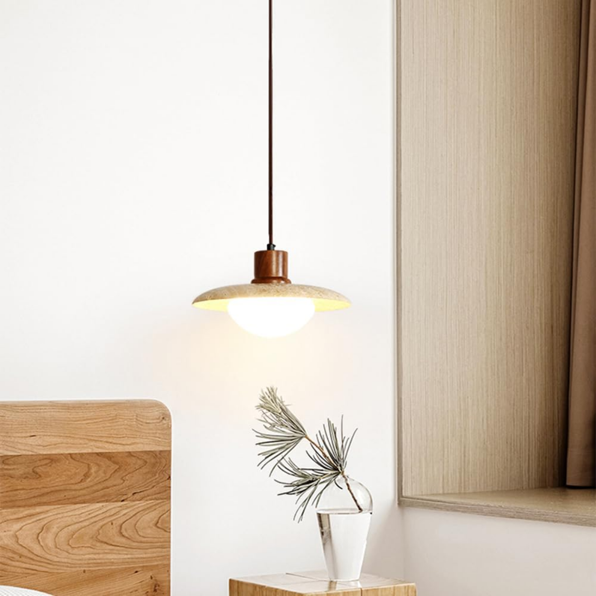 Aurelia Wabi-Sabi Travertine Pendant Light hanging beside a bed with wood side table and vase