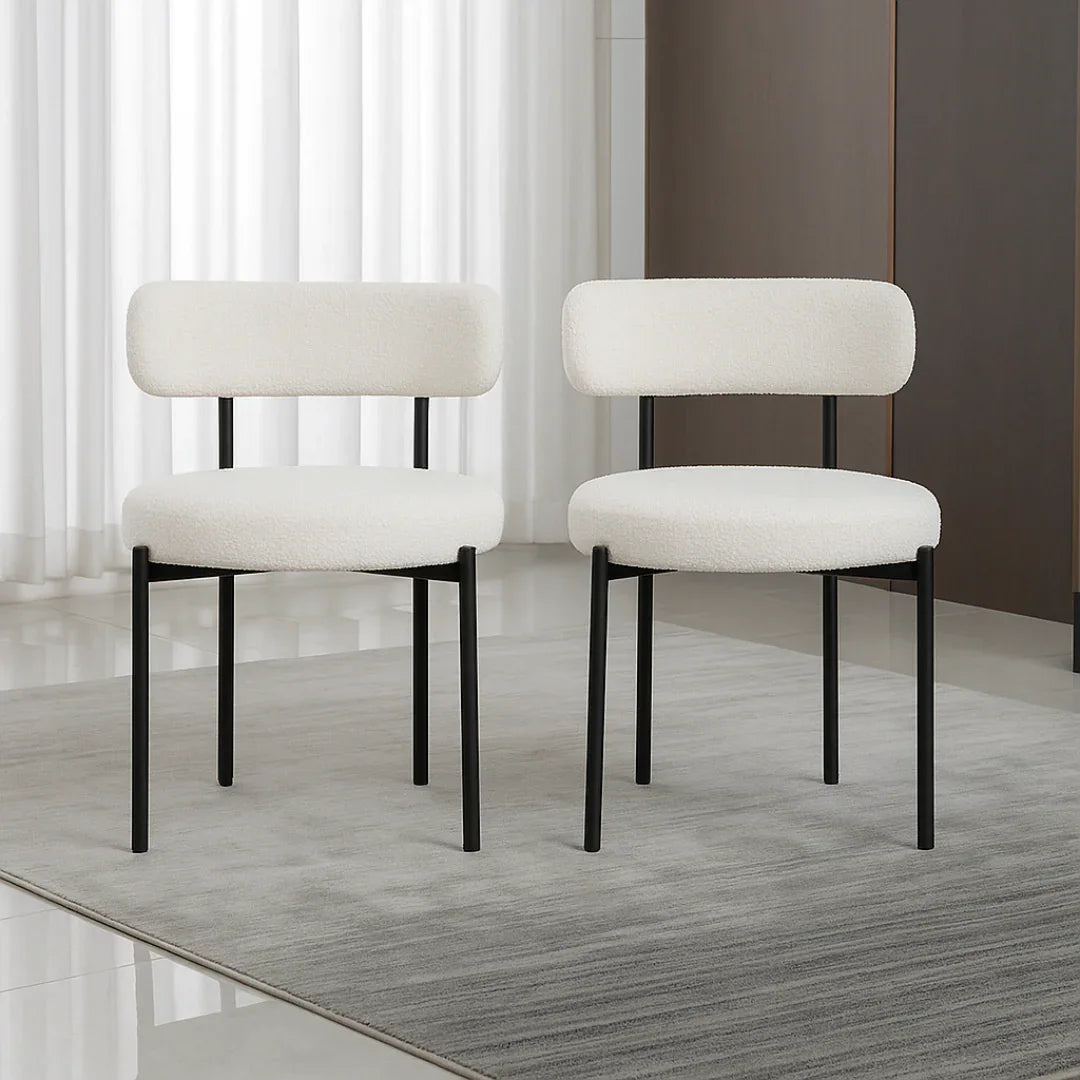Two white chairs with black legs on a wooden floor.