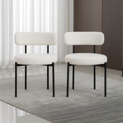 Two white chairs with black legs on a wooden floor.