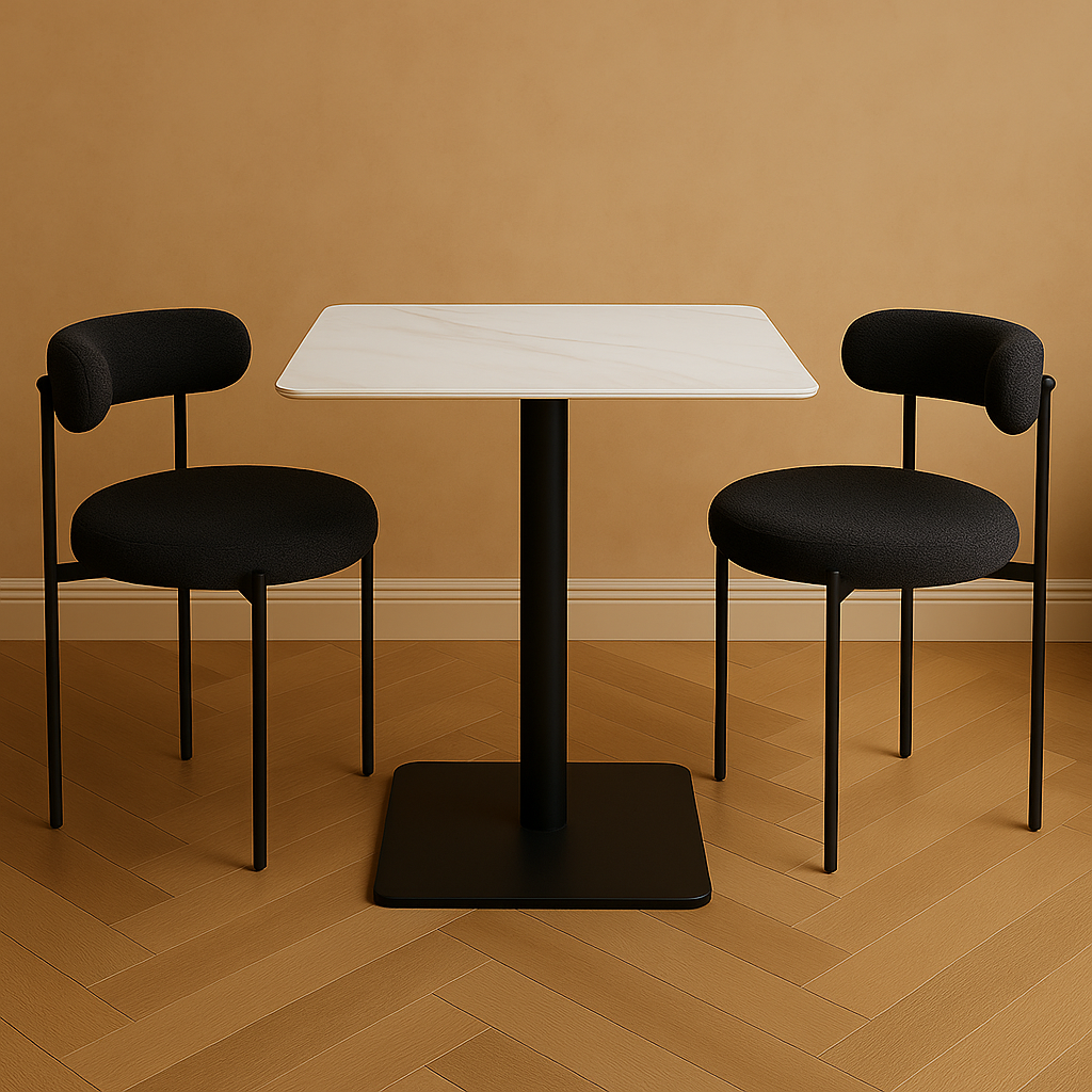 Two black chairs with cushioned seats and backrests are arranged around a white square table on a wooden floor.