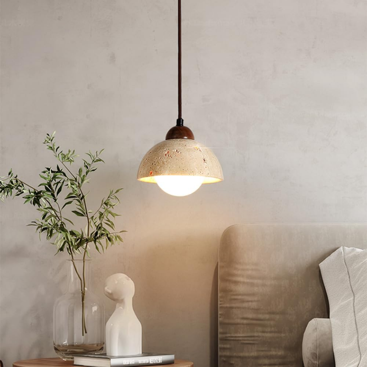 Aurelia Travertine Dome Pendant Light hanging above a bedside table with plant and sofa