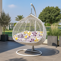 White hanging egg chair with a floral cushion on a patio