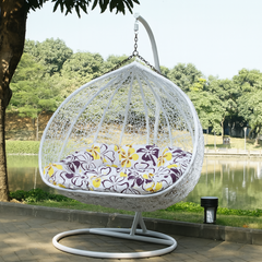 White hanging egg chair with floral cushion in a garden setting