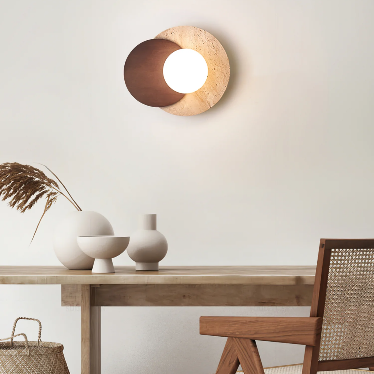 Lunara Travertine Stone & Wood Lunar Eclipse Wall Light installed above a dining table with vases and a rattan chair