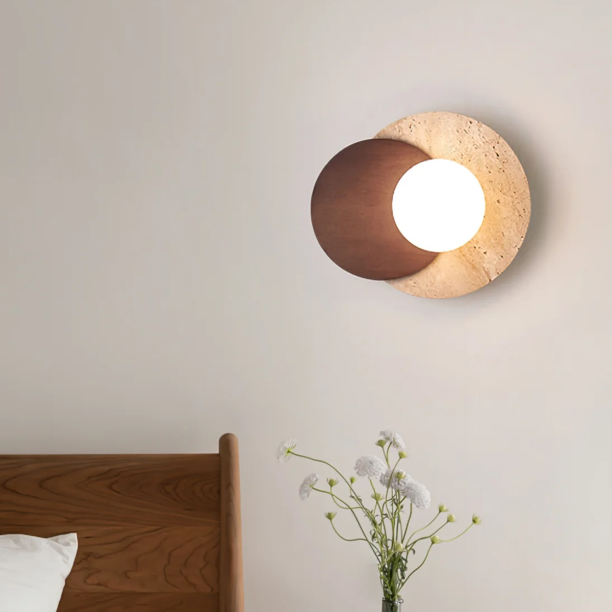 Lunara Travertine Stone & Wood Lunar Eclipse Wall Light installed above a wooden bed headboard with white flowers