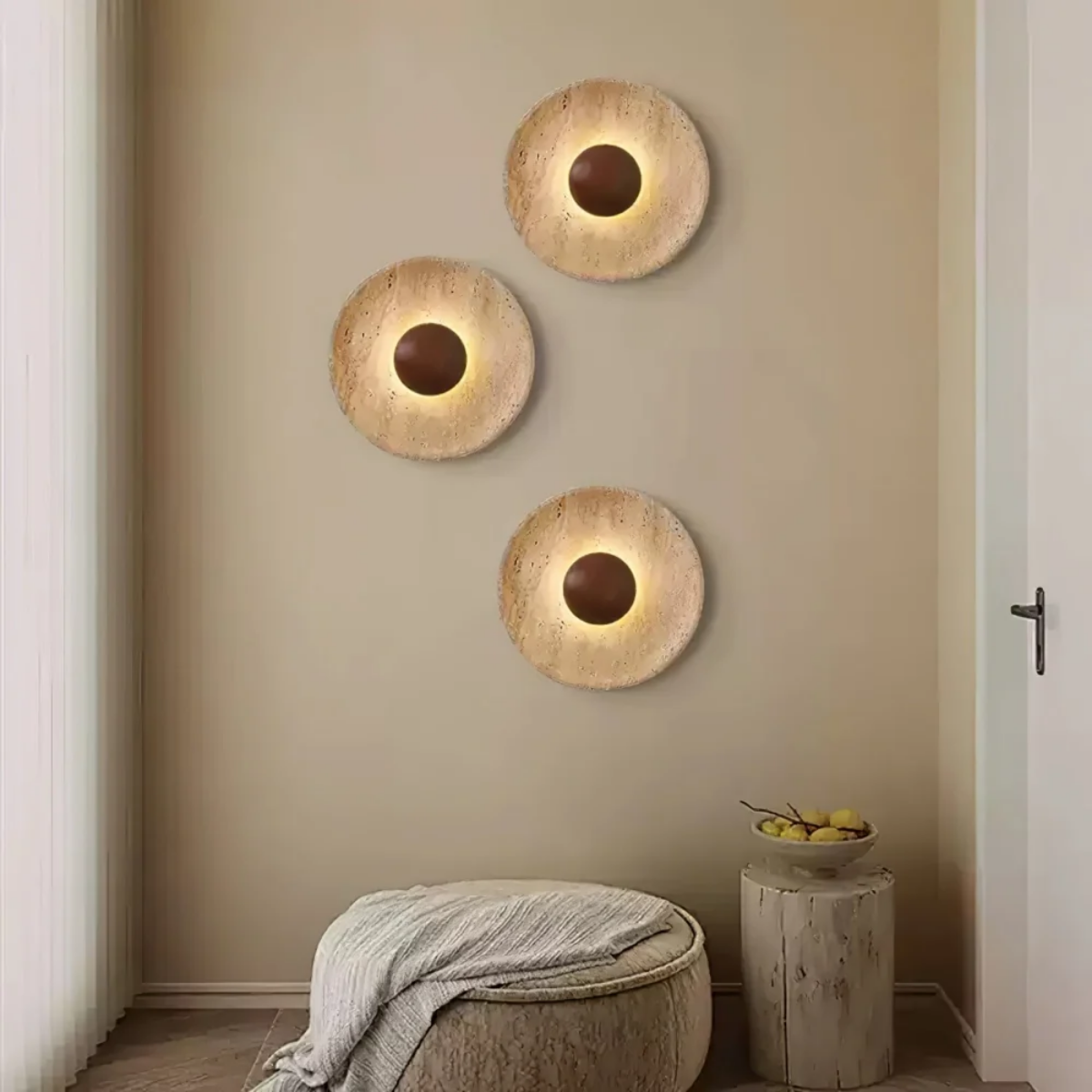 Three Solara Travertine Round Wall Lights arranged diagonally above a living room ottoman and side table