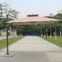 Large beige patio umbrella on a wooden deck with trees and buildings in the background