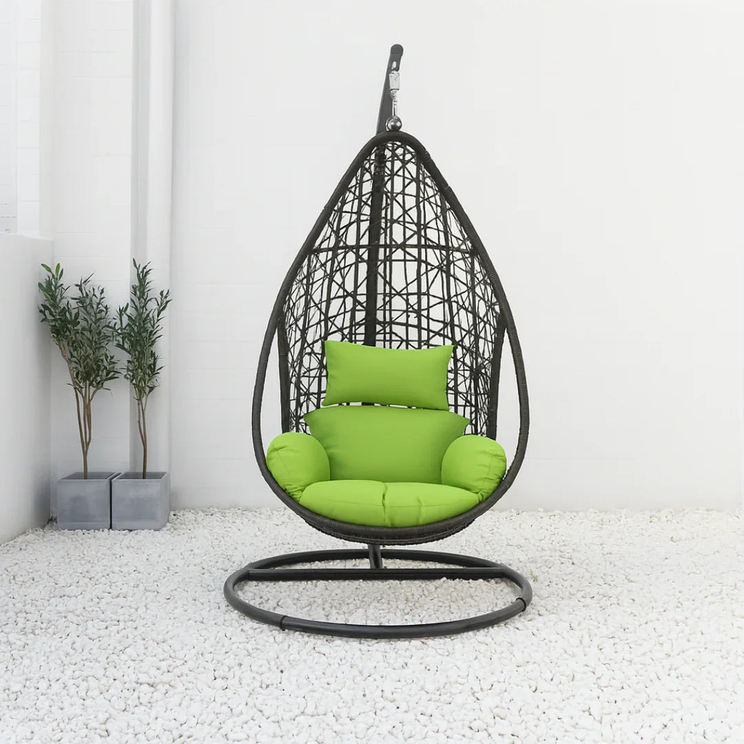 Hanging chair with green cushions on a white floor and light gray walls
