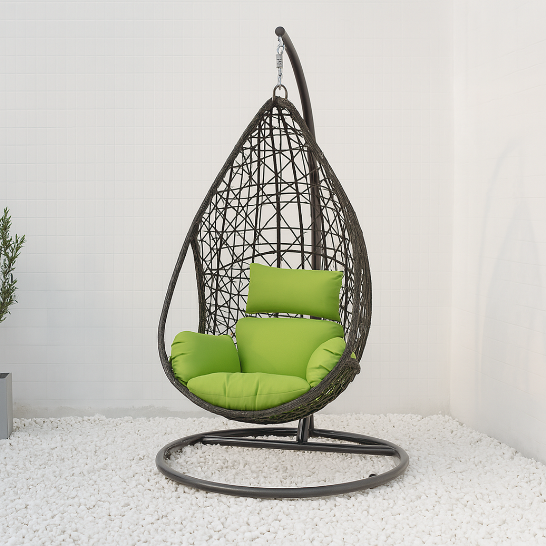 Hanging egg chair with green cushions on a white pebble floor.