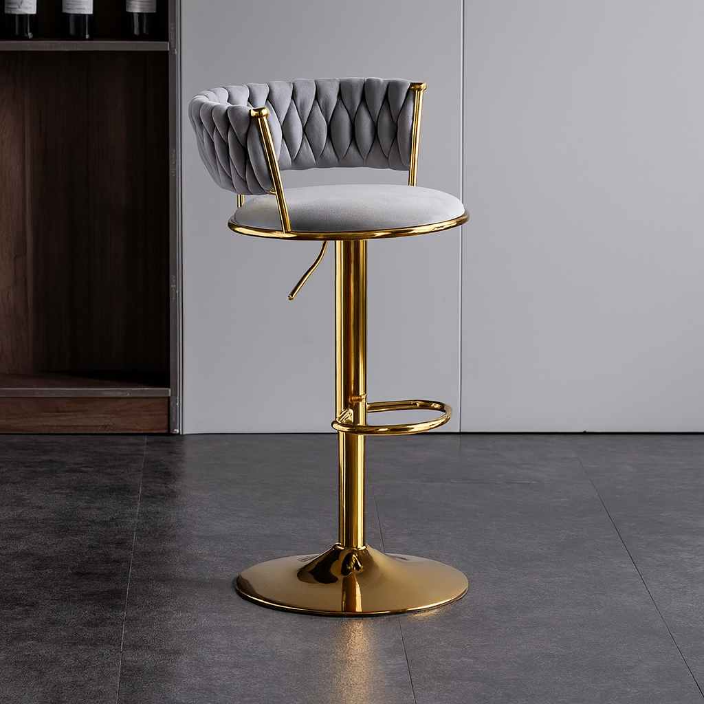 Gray cushioned bar stool with gold base on a gray floor.
