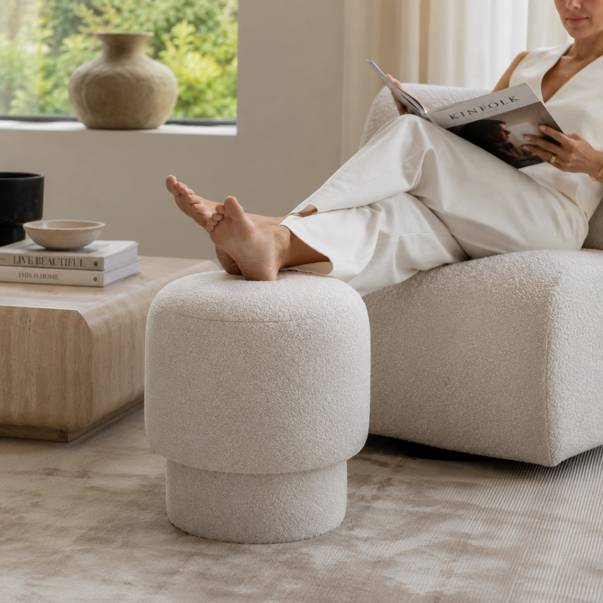 Person resting feet on Wooden Twist Mushroom Bouclé Ottoman Stool in Off White – lifestyle with model